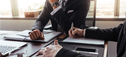 People witting at a meeting table with documents and devices