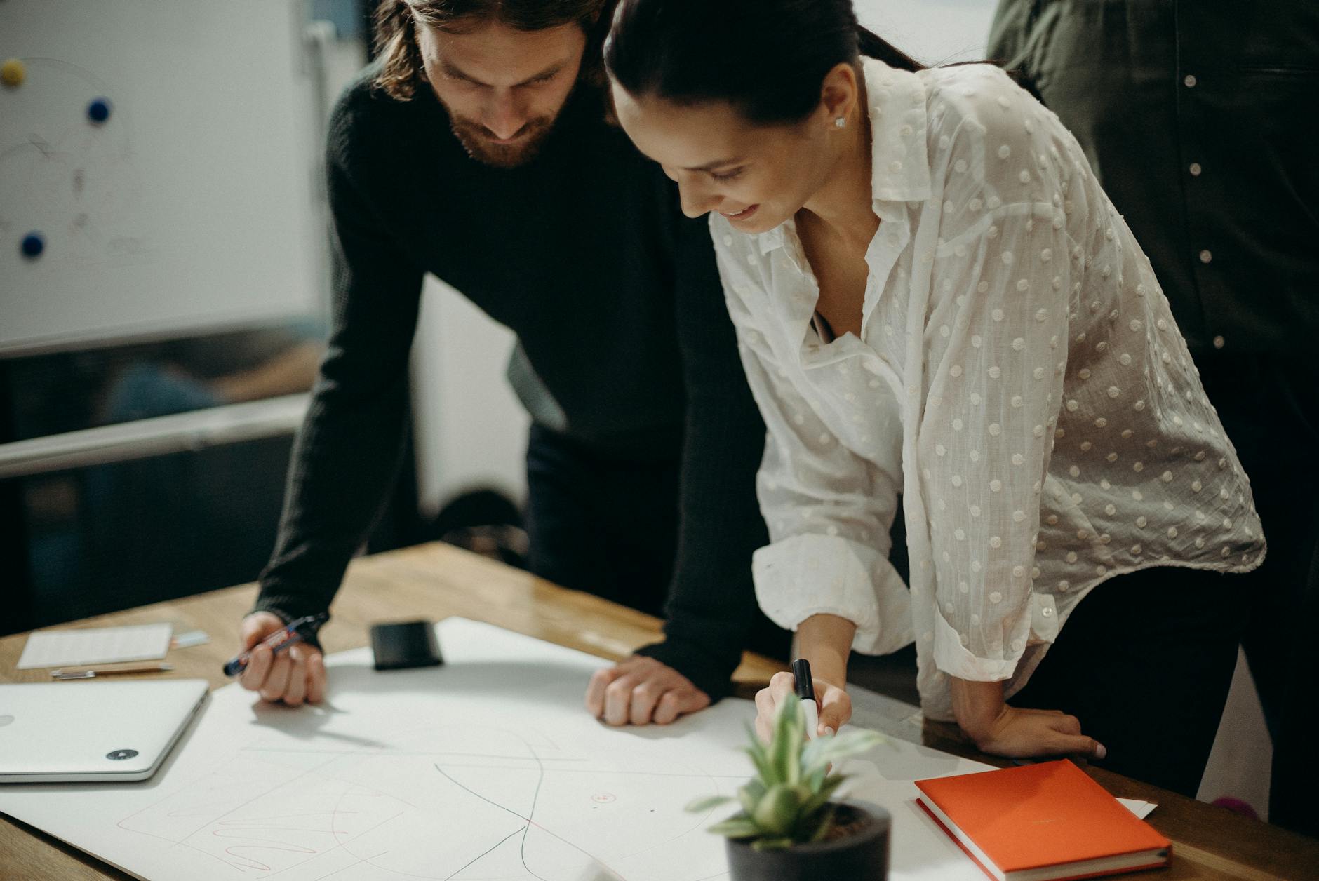 man and woman leaning on table staring at white board on top of table